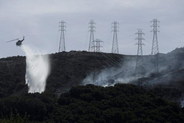A helicopter drops water near power lines and electrical towers while working at a fire on San Bruno Mountain near Brisbane, Calif., on Oct. 10, 2019. (Jeff Chiu/AP Photo)