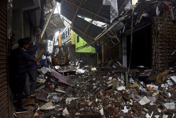 People use their mobile phones to take pictures of a collapsed building following rains in Mumbai, India, on July 23, 2021. (Stringer/Reuters)