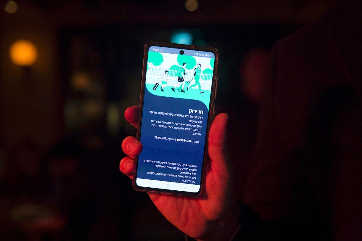 An Israeli man holds his smart phone as he is presenting a COVID-19 vaccination certificate named "Green Pass" before entering a bar in Tel Aviv, Israel, on March 17, 2021. (Amir Levy/Getty Images)