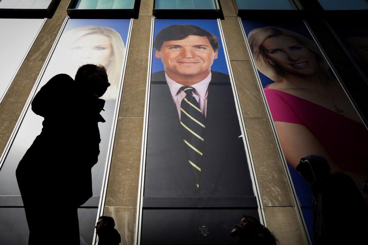 People pass by a promotion of Fox News host Tucker Carlson on the News Corporation building in New York on March 13, 2019. (Brendan McDermid/Reuters)