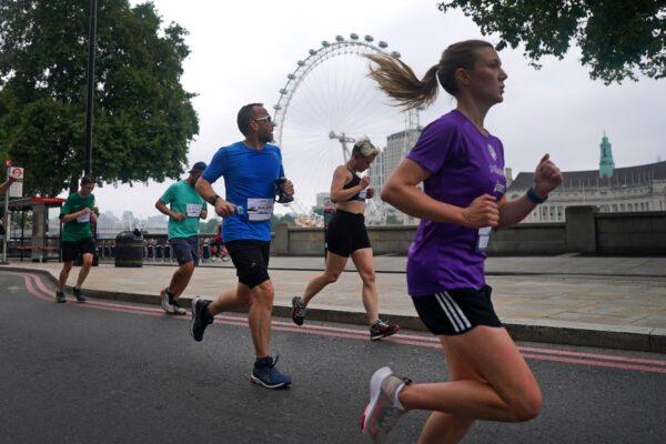 Runners pass along the Embankment in front of the London Eye as they take part in the Asics London 10k, thought to be the largest closed road running event in London since the March 2020 lockdown, in London on July 25, 2021. (Victoria Jones/PA)