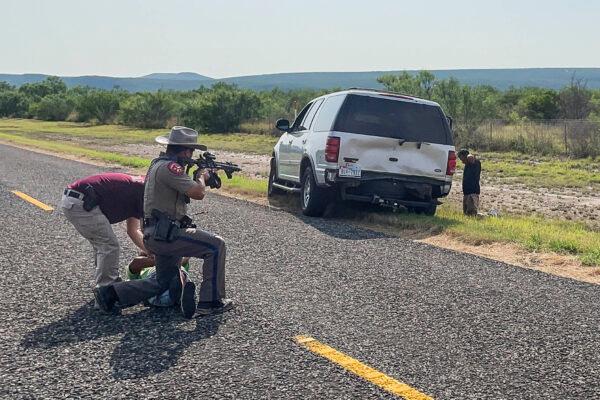 A Texas State Trooper and the Kinney County Constable arrest the Honduran driver (on ground) and passenger (right) of a stolen truck in Kinney County, Texas, on July 21, 2021. (Charlotte Cuthbertson/The Epoch Times)