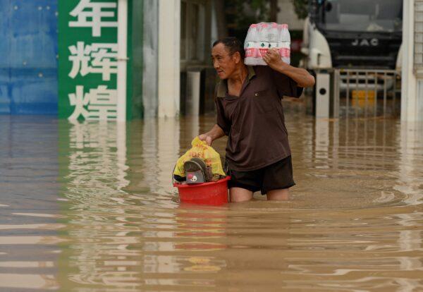 A man carries bottled water as he crosses a flooded street in Zhengzhou, a city in China's Henan Province on July 23, 2021. (Noel Celis/AFP via Getty Images)