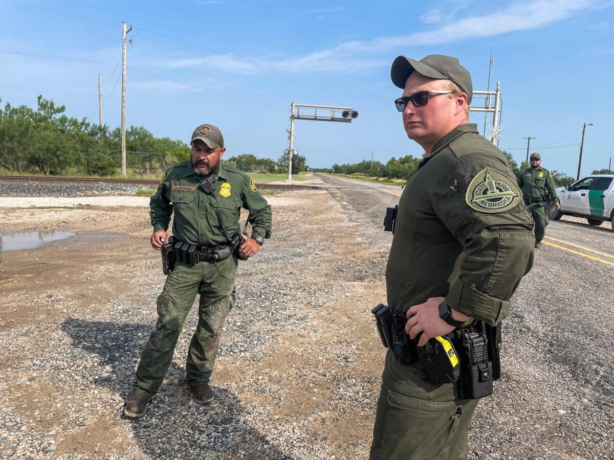 A Nebraska State Trooper (C) assists Border Patrol in detaining illegal immigrants while deployed to Texas, in Kinney County, Texas, on July 21, 2021. (Charlotte Cuthbertson/The Epoch Times)
