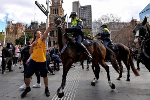 A protester (L) tries to push away a police horse in Sydney, Australia, on July 24, 2021. (Steven Saphore/AFP via Getty Images)