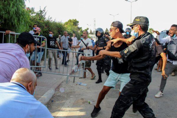 Tunisian police officers scuffle with demonstrators as they gather outside the parliament in Tunis, Tunisia, on July 26, 2021. (Hedi Azouz/AP Photo)