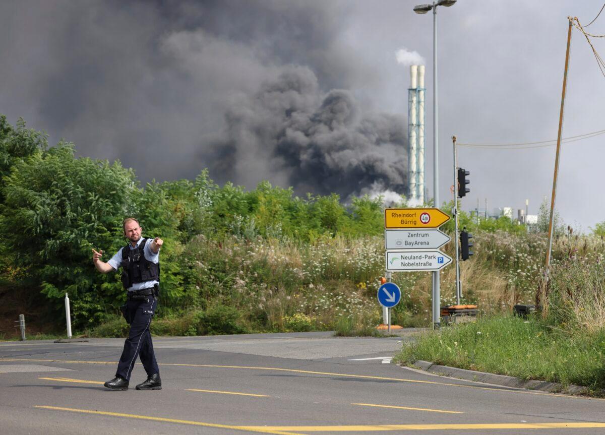 A police officer blocks an access road to the Chempark after an explosion in Leverkusen, Germany, on July 27, 2021. (Oliver Berg/dpa via AP)