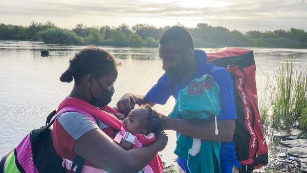 A Haitian couple with a 4-month-old baby prepare to illegally cross the Rio Grande into Del Rio, Texas, from Acuna, Mexico, on July 25, 2021. (Charlotte Cuthbertson/The Epoch Times)