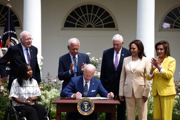 President Joe Biden signs a proclamation on the anniversary of the Americans with Disabilities Act (ADA), as (L-R) artist Tyree Brown, Sen. Pat Leahy (D-VT), former Rep. Tony Coelho (D-CA), House Majority Leader Steny Hoyer (D-MD), U.S. Vice President Kamala Harris, and House Speaker Nancy Pelosi (D-CA) look on in the Rose Garden of the White House in Washington, DC on July 26, 2021. (Anna Moneymaker/Getty Images)