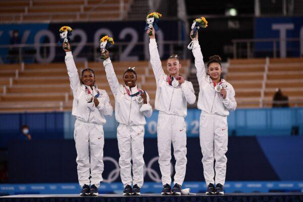 USA's Sunisa Lee, USA's Grace Mc Callum USA's Simone Biles and USA's Jordan Chiles wave on the podium of the artistic gymnastics women's team final after winning silver during the Tokyo Olympics in Tokyo, Japan on July 27, 2021. (Loic Venance/AFP via Getty Images)