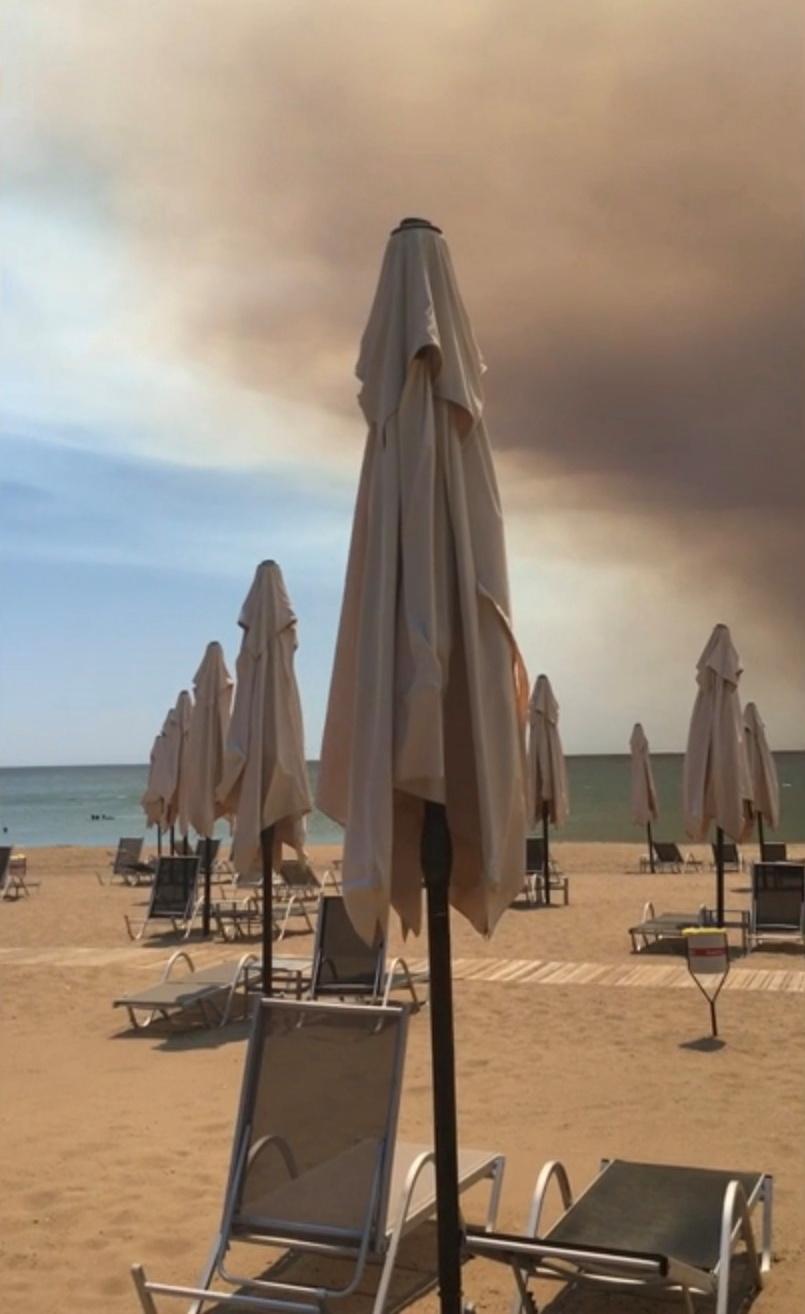 Smoke from a wildfire hovers over the beach in this still image taken from social media video in Manavgat, Antalya, Turkey, on July 28, 2021. (Twitter/@Onurburakcelik/via Reuters)