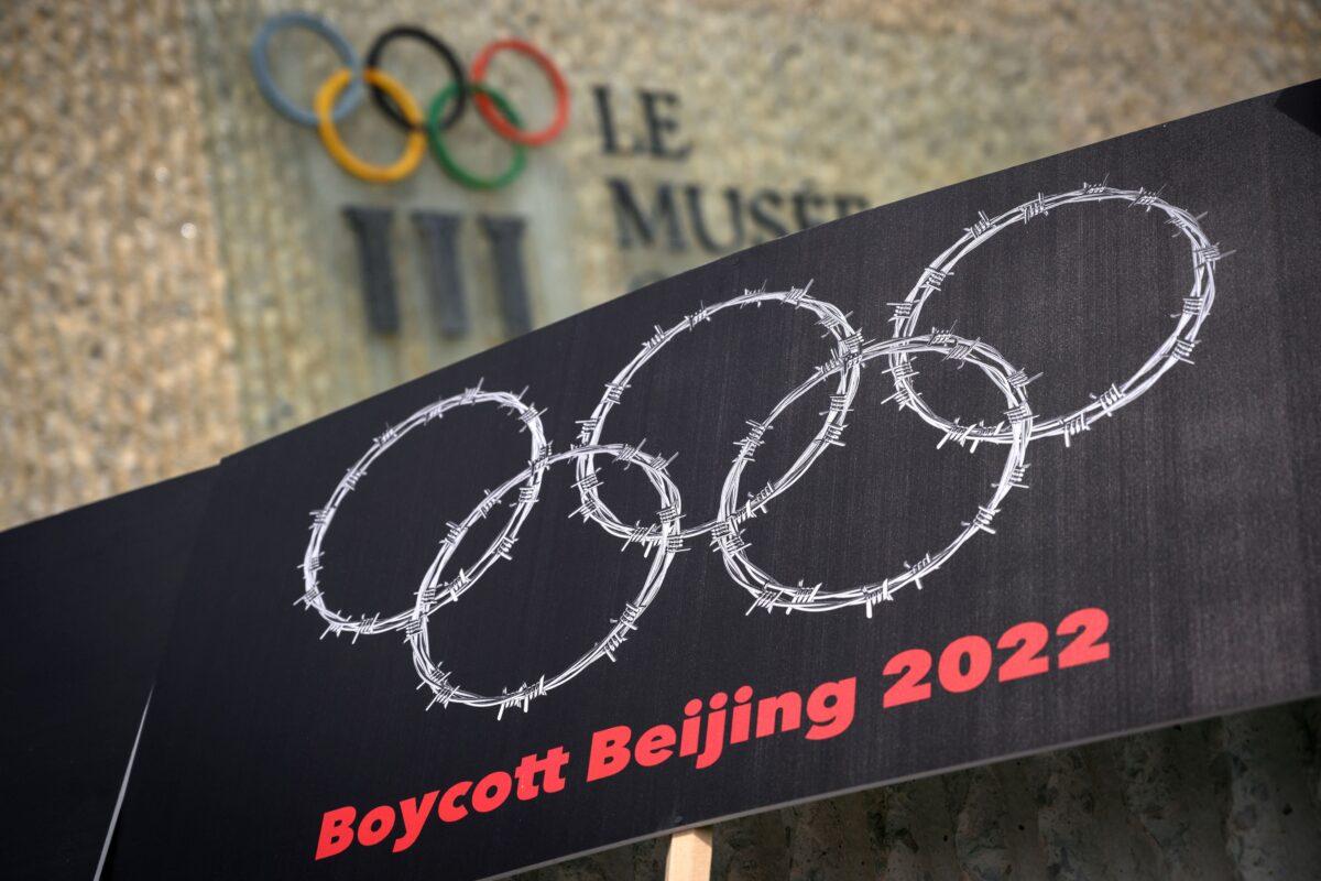 A placard showing barbed wire shaping the Olympics Rings next to a sign of the Olympics Museum during a protest organized by Tibetan and Uyghur activists against the Beijing 2022 Winter Olympics, in Lausanne, Switzerland, on June 23, 2021. (Fabrice Coffrini/AFP via Getty Images)
