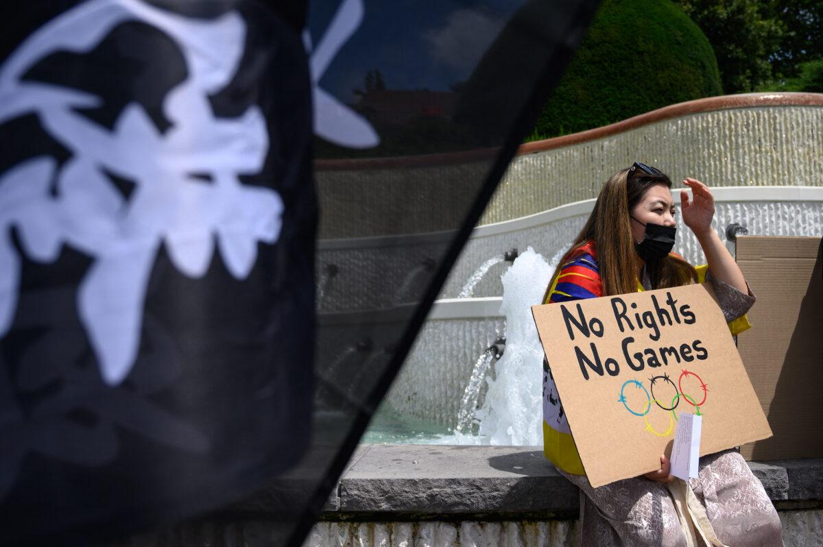 A woman holds a placard during a protest against Beijing 2022 Winter Olympics by Tibetan and Uyghur activists in front of the Olympics Museum in Lausanne as some 200 participants took part in the protest on June 23, 2021. (Fabrice Coffrini/AFP via Getty Images)