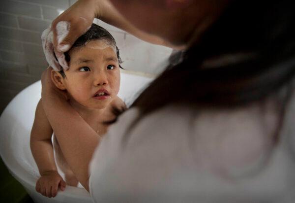 A young Chinese orphaned girl is bathed by a worker at a foster care center in Beijing, China, on April 2, 2014. (Kevin Frayer/Getty Images)