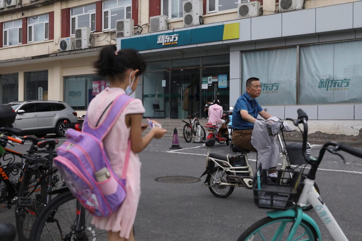 A girl carrying a schoolbag stands near an outlet of private educational services provider New Oriental Education and Technology Group in Beijing, China, on July 26, 2021. (Tingshu Wang/Reuters)