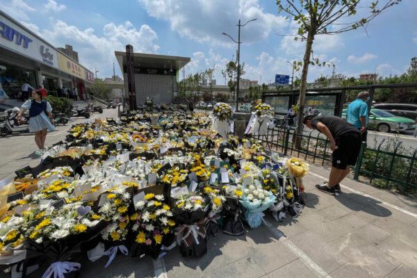 A man bows as people place flowers in front of a subway station in memory of flood victims in Zhengzhou, China's central Henan Province on July 27, 2021.