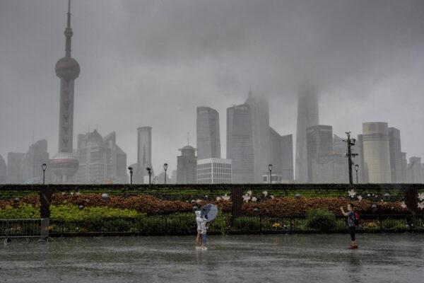 People pose for a photo along an empty Bund in Shanghai, as most people stay indoors due to wind and rain caused by Typhoon In-fa whips parts of the eastern Chinese coast on July 25, 2021. (Vivian Lin / AFP)
