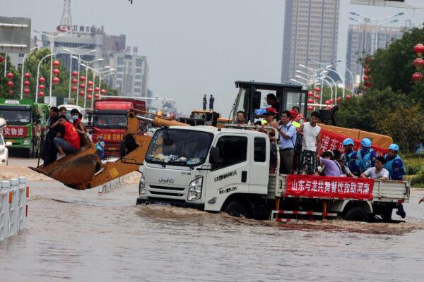 This photo taken on July 26, 2021 shows rescuers evacuating residents with a truck at a flooded area in the city of Weihui in China's central Henan Province. (STR/AFP via Getty Images)