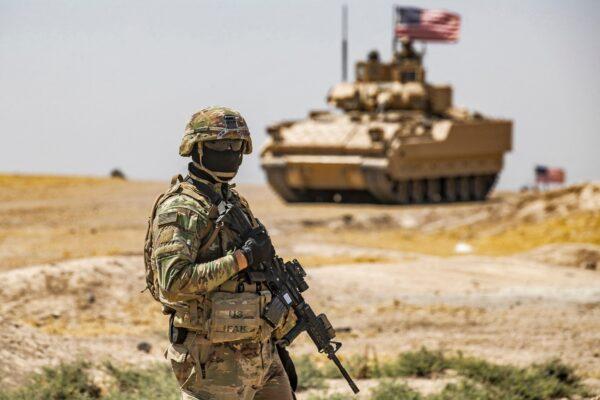 A U.S. soldier stands near a Bradley Fighting Vehicle (BFV) during a patrol near the Rumaylan (Rmeilan) oil wells in Syria's northeastern Hasakeh province on June 22, 2021. (Delil Soulieman/AFP via Getty Images)