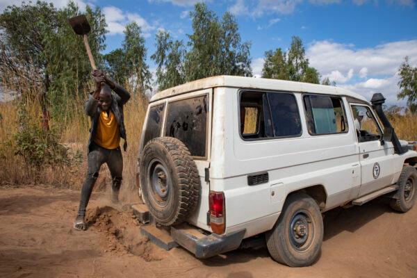 A local villager helps dig out the rear of a Water Wells for Africa 4x4 in Malawi's Machinga District on July 8, 2021. (John Fredricks/The Epoch Times)