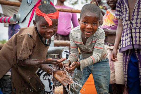 Children enjoy clean water from a well built by Water Wells for Africa in Lupapa Village, Malawi, on July 6, 2021. (John Fredricks/The Epoch Times)