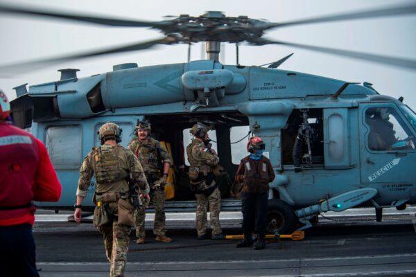 Sailors on board an MH-60S Seahawk helicopter on the flight deck of aircraft carrier USS Ronald Reagan prepare to head to an oil tanker that was attacked off the coast of Oman in the Arabian Sea on July 30, 2021. (Mass Communication Specialist 2nd Class Quinton A. Lee/U.S. Navy via AP)