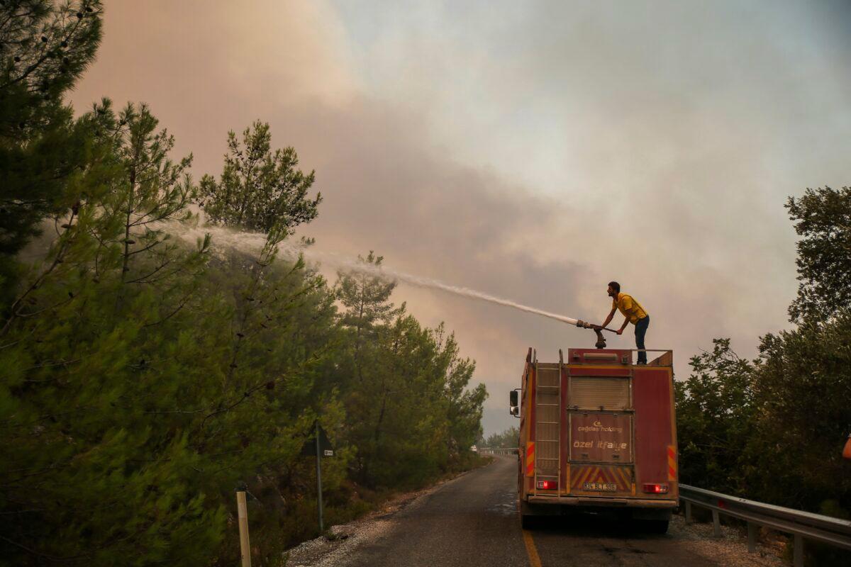 Firefighters work in the smoke-engulfed Mazi area as wildfires rolled down the hill toward the seashore, forcing people to be evacuated, in Bodrum, Mugla, Turkey, on Aug. 1, 2021. (Emre Tazegul/AP Photo)