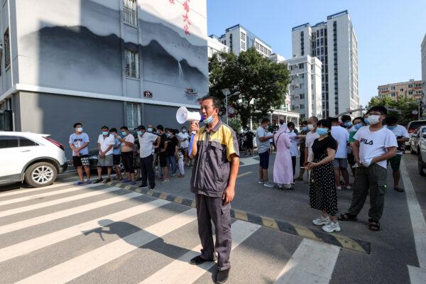 A man maintains order with a speaker as residents queue to receive the tests for COVID-19 in Zhengzhou, Central China's Henan Province on July 31, 2021. (AFP via Getty Images)
