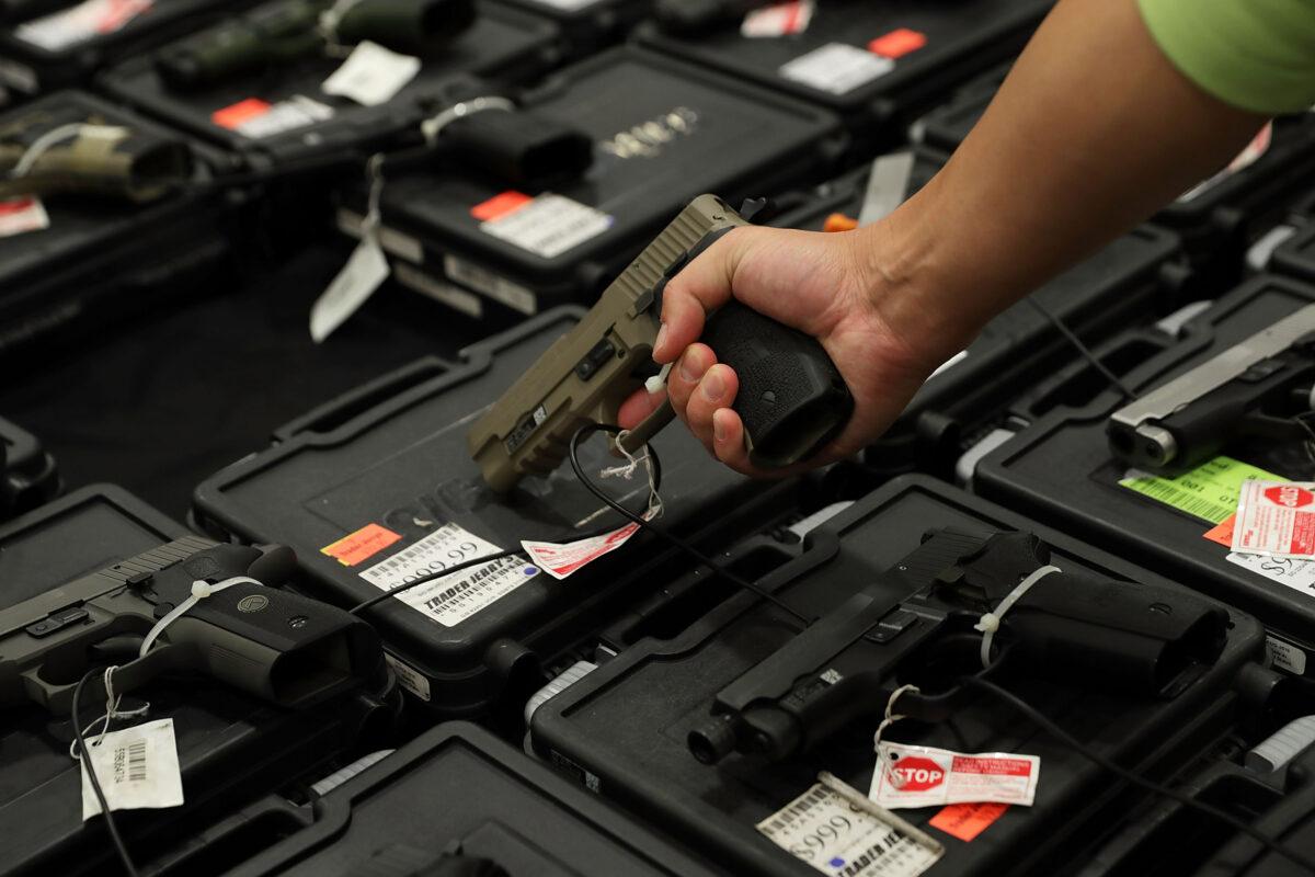 A potential buyer handles a gun that is displayed on an exhibitor's table during the Nation's Gun Show at Dulles Expo Center in Chantilly, Va., on Nov. 18, 2016. (Alex Wong/Getty Images)