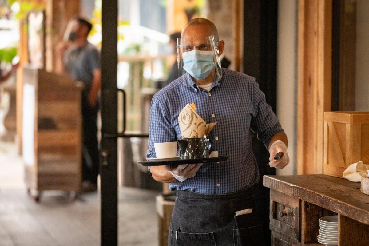 A waiter carries food at The Farmhouse restaurant in Newport Beach, Calif., on Sept. 9, 2020. (John Fredricks/The Epoch Times)