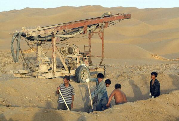 Workers are digging a well for underground water in the Taklamakan Desert, outside of Tazhong town in Qiemo county in northwestern China's Xinjiang Region on Sept. 13, 2003. (Frederic J. Brown/AFP via Getty Images)