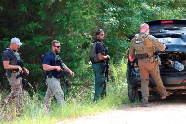 Greenwood County deputies carried rifles as they searched the tree line and area surrounding where three people were killed and one person injured in a shooting in Greenwood, S.C., on Aug. 2, 2021. (Damian Dominguez/The Index-Journal via AP)