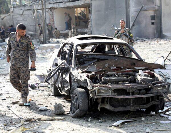 A member of Afghan security forces looks at a damaged car at the site of the Aug. 3 car bomb blast in Kabul, Afghanistan, on Aug. 4, 2021. (Stringer/Reuters)