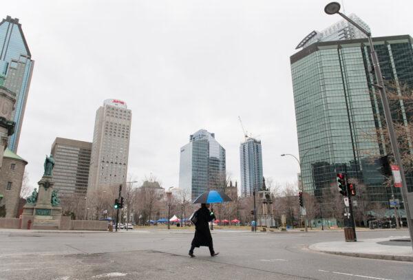 A woman crosses an empty street in downtown Montreal on April 5, 2020. (The Canadian Press/Graham Hughes)