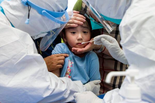 A child reacts to a throat swab during mass testing for COVID-19 in Wuhan in central China's Hubei Province, on Aug. 3, 2021. (Chinatopix/via AP)