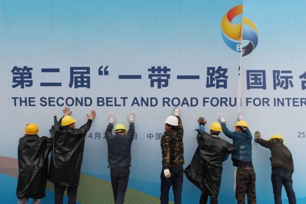 Workers take down a Belt and Road Forum panel outside the venue of the forum in Beijing on April 27, 2019. (Greg Baker/AFP via Getty Images)