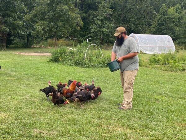 Travis Maddox, a prepper and producer of The Prepared Homestead on YouTube, feeds his chickens. (Courtesy Travis Maddox)