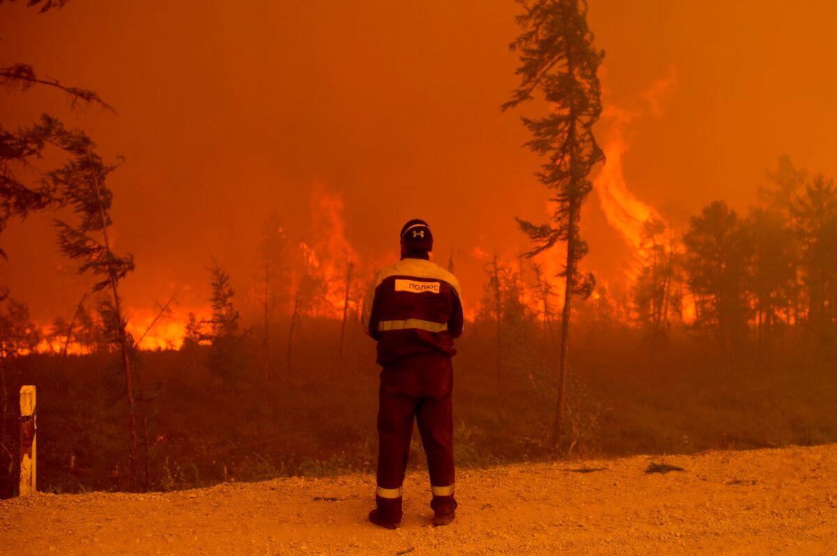 A firefighter stands at the scene of forest fire near Kyuyorelyakh village at Gorny Ulus area west of Yakutsk, in Russia, on Aug. 7, 2021. (Ivan Nikiforov/AP Photo)
