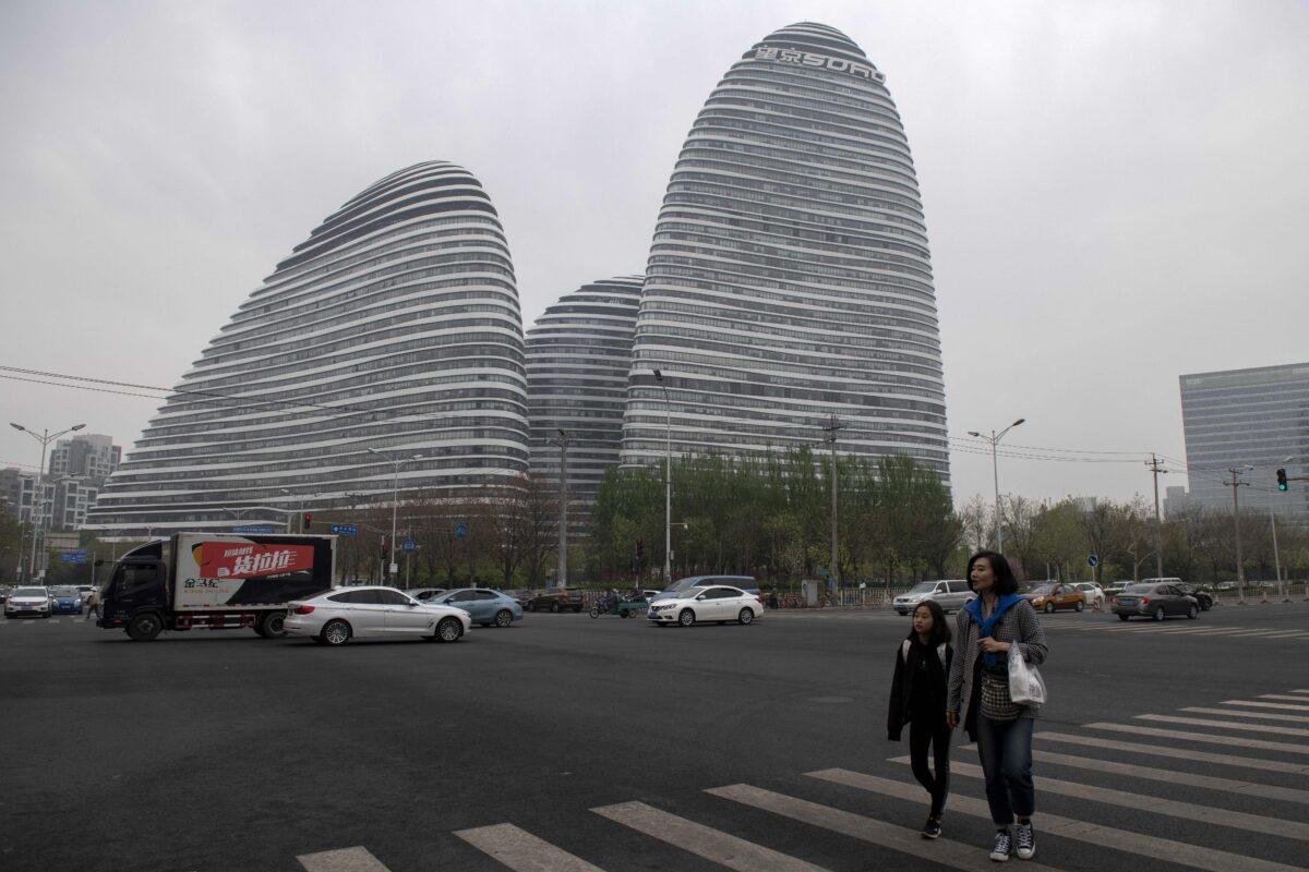 The Wangjing SOHO development, designed by the late Iraqi-British architect Zaha Hadid, is seen as pedestrians walk across a zebra crossing in Beijing on April 13, 2019. (Nicolas Asfouri/AFP via Getty Images)