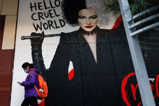 A masked pedestrian walks past a poster for the film Cruella in downtown Melbourne, Australia on Aug. 6, 2021, amid a sixth lockdown for the city (Con Chronis/AFP via Getty Images)