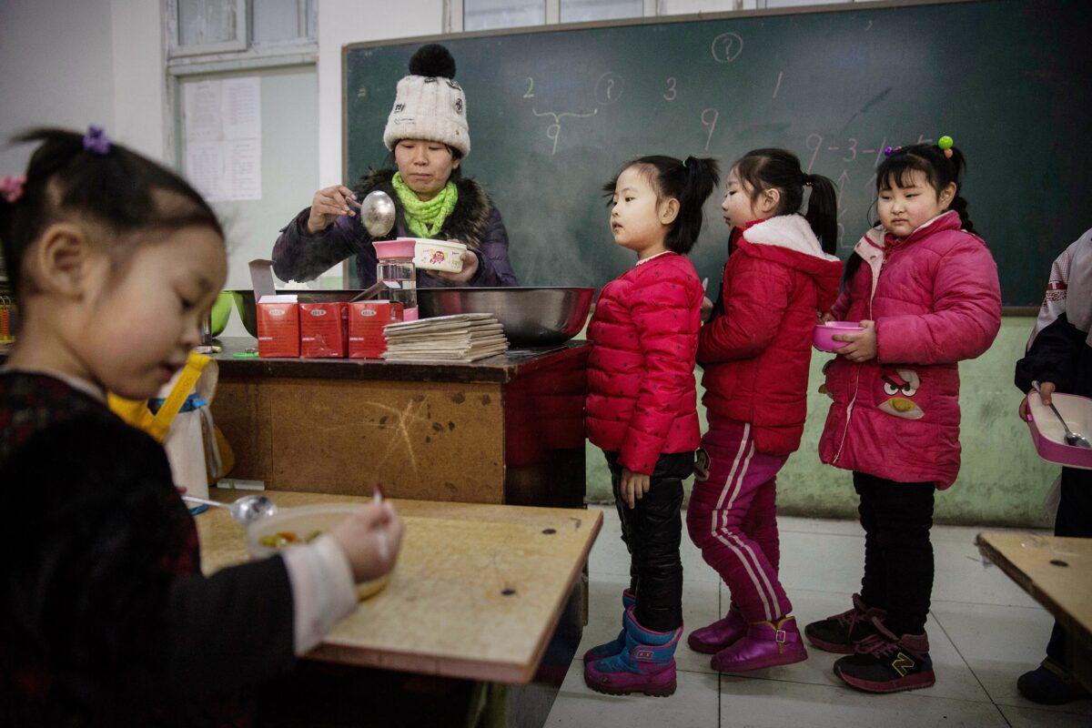 Chinese students who are children of migrants wait in line for lunch in a classroom at an unofficial school in Beijing on Dec. 18, 2015. Schools for children of migrants are often unofficial or unrecognized by the state and were established as a response to the education void created by the decades-long household registration or hukou system. A person's hukou entitles them to social services in their birthplace, meaning millions of Chinese who have migrated from rural areas to cities have been denied rights to urban public services. (Kevin Frayer/Getty Images)