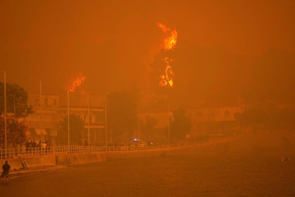 Fire burns trees near a beach at Pefki village on Evia island, about 189 kilometers (118 miles) north of Athens, Greece, on Aug. 8, 2021. (Petros Karadjias/AP Photo)