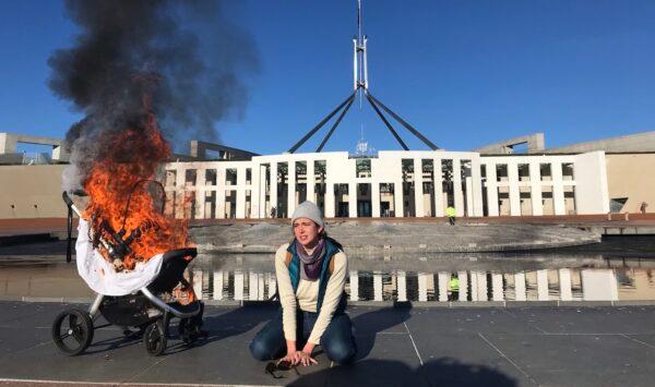 An Extinction Rebellion protestor beside a burning pram outside Parliament House that was vandalised following an Intergovernmental Panel on Climate Change report which suggested more needed to be done to address climate concerns on Aug. 10, 2021, Canberra, Australia (AAP Image/Supplied by Extinction Rebellion)