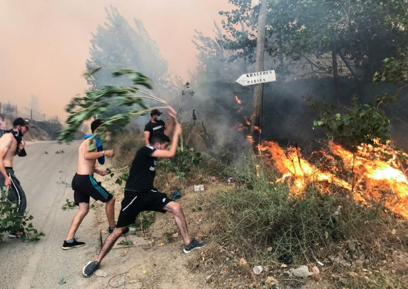 People attempt to put out a fire in the mountainous Tizi Ouzou province, east of Algiers, Algeria on Aug. 10, 2021. (Abdelaziz Boumzar/Reuters)