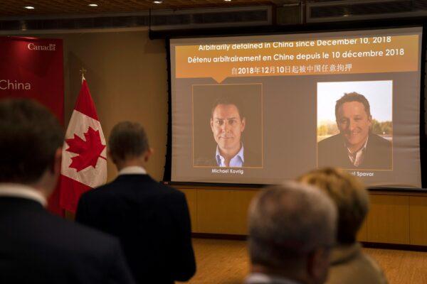 A video screen displays images of Canadians Michael Kovrig (L) and Michael Spavor at an event held in connection with the announcement of the sentence for Spavor at the Canadian Embassy in Beijing, China, on Aug. 11, 2021. (AP Photo/Mark Schiefelbein)