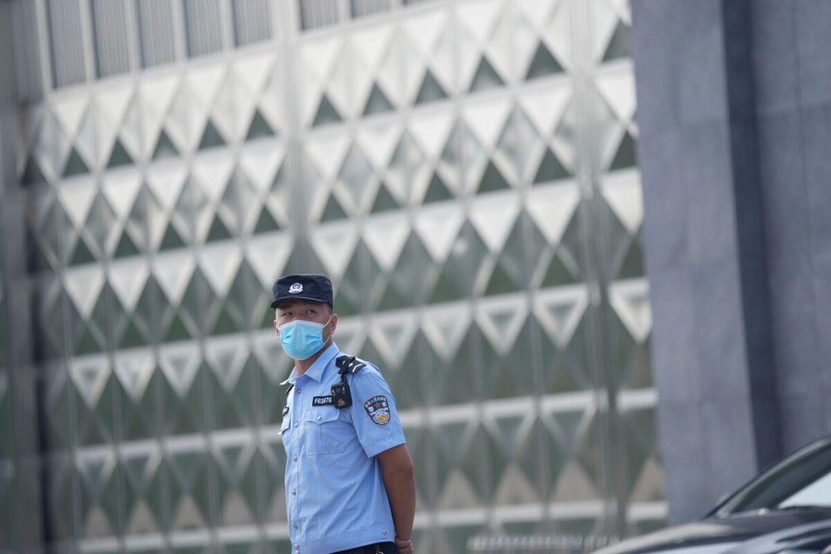 A policeman wearing a face mask stands guard outside a detention center where Dominic Barton, Ambassador of Canada to China will meet Canadian Michael Spavor, in Dandong, China, Wednesday, Aug. 11, 2021. A Chinese court has sentenced Michael Spavor to 11 years on spying charges in case linked to Huawei. (AP Photo/Ng Han Guan)