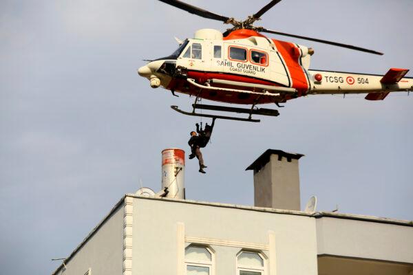 A Coast Guard helicopter rescue a man stranded on the rooftop of a building after floods forced people to seek safety on high ground and mudslides killed several people, in Bozkurt town of Kastamonu province, Turkey, on Aug. 12, 2021. (IHA via AP)