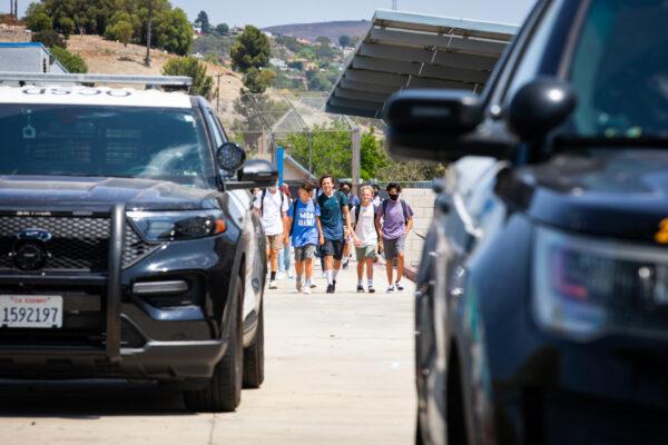 Children walk toward Orange County Sheriff's Department vehicles as they depart Hewes Middle School in Santa Ana, Calif., on Aug. 2, 2021. (John Fredricks/The Epoch Times)