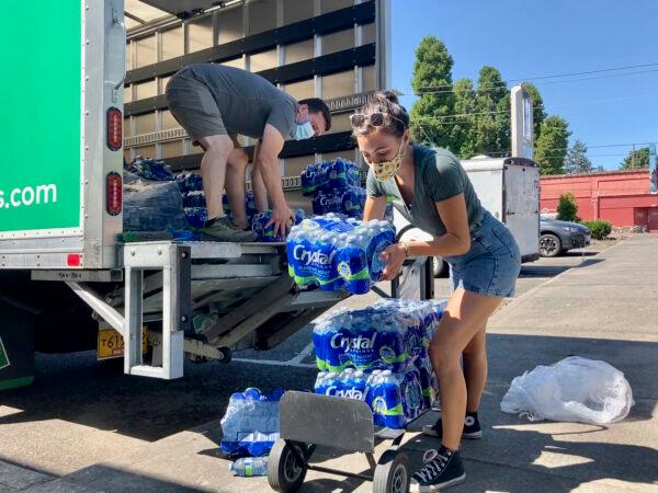 Volunteers and Multnomah County employees unload cases of water to supply a 24-hour cooling center set up in Portland, Ore., on Aug. 11, 2021. (Gillian Flaccus/AP Photo)