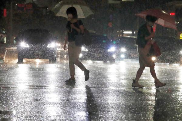 People holding umbrella make their way through heavy rain in Fukuoka, western Japan, on Aug. 12, 2021. (Kyodo News via AP)